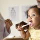 parent and doctor showing child how to brush teeth